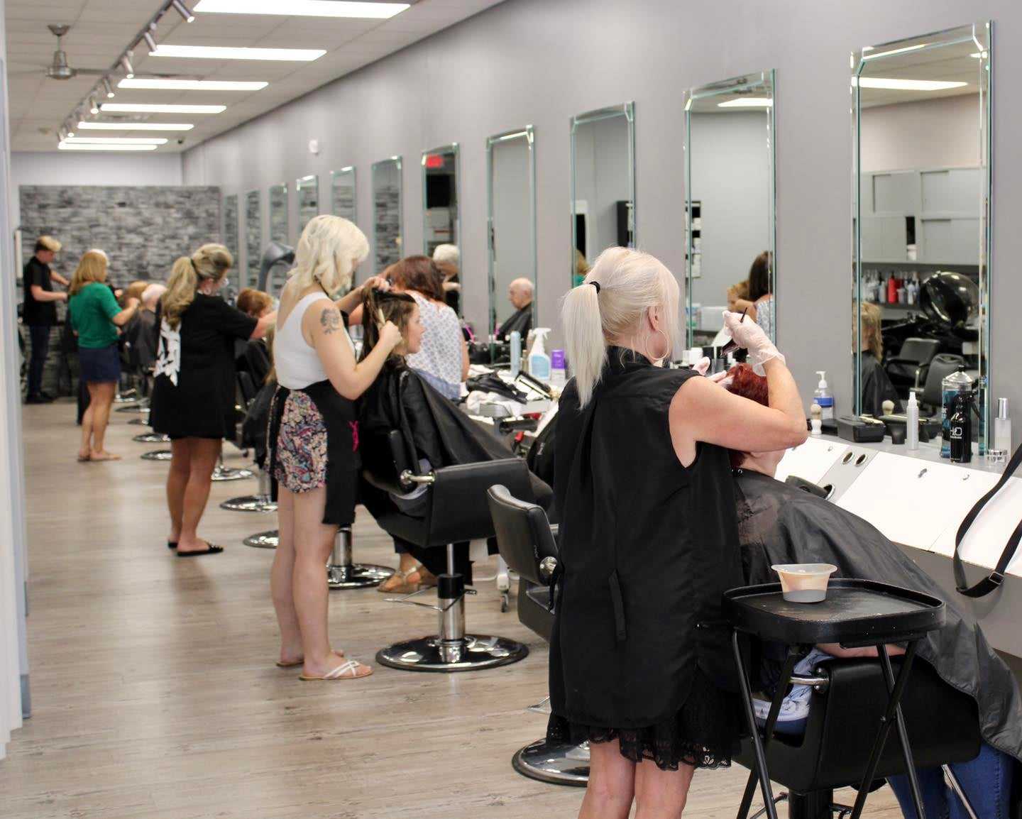 A busy hair salon with stylists cutting and coloring clients' hair.